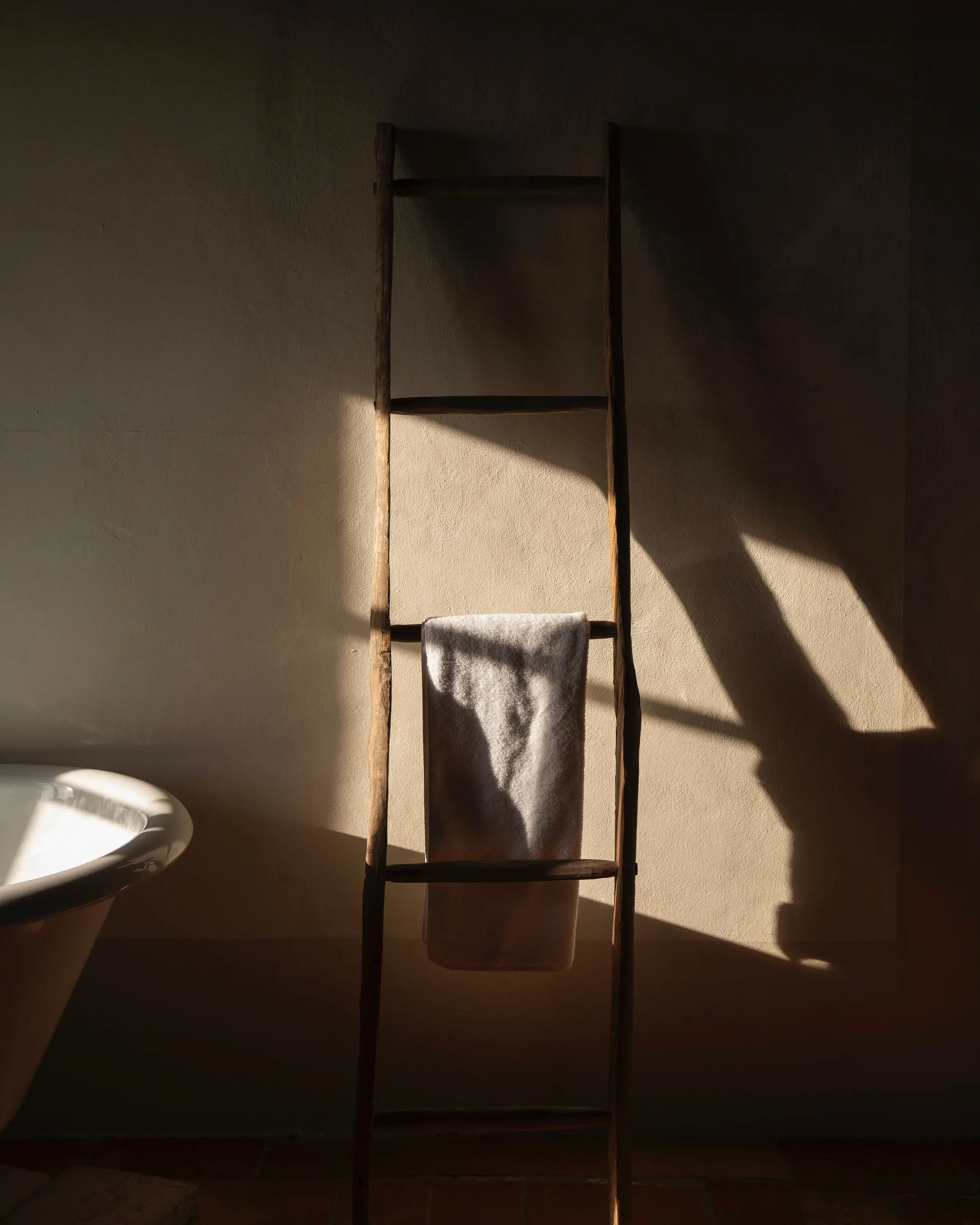 Late sun casting long shadows from a timber ladder in the bathroom