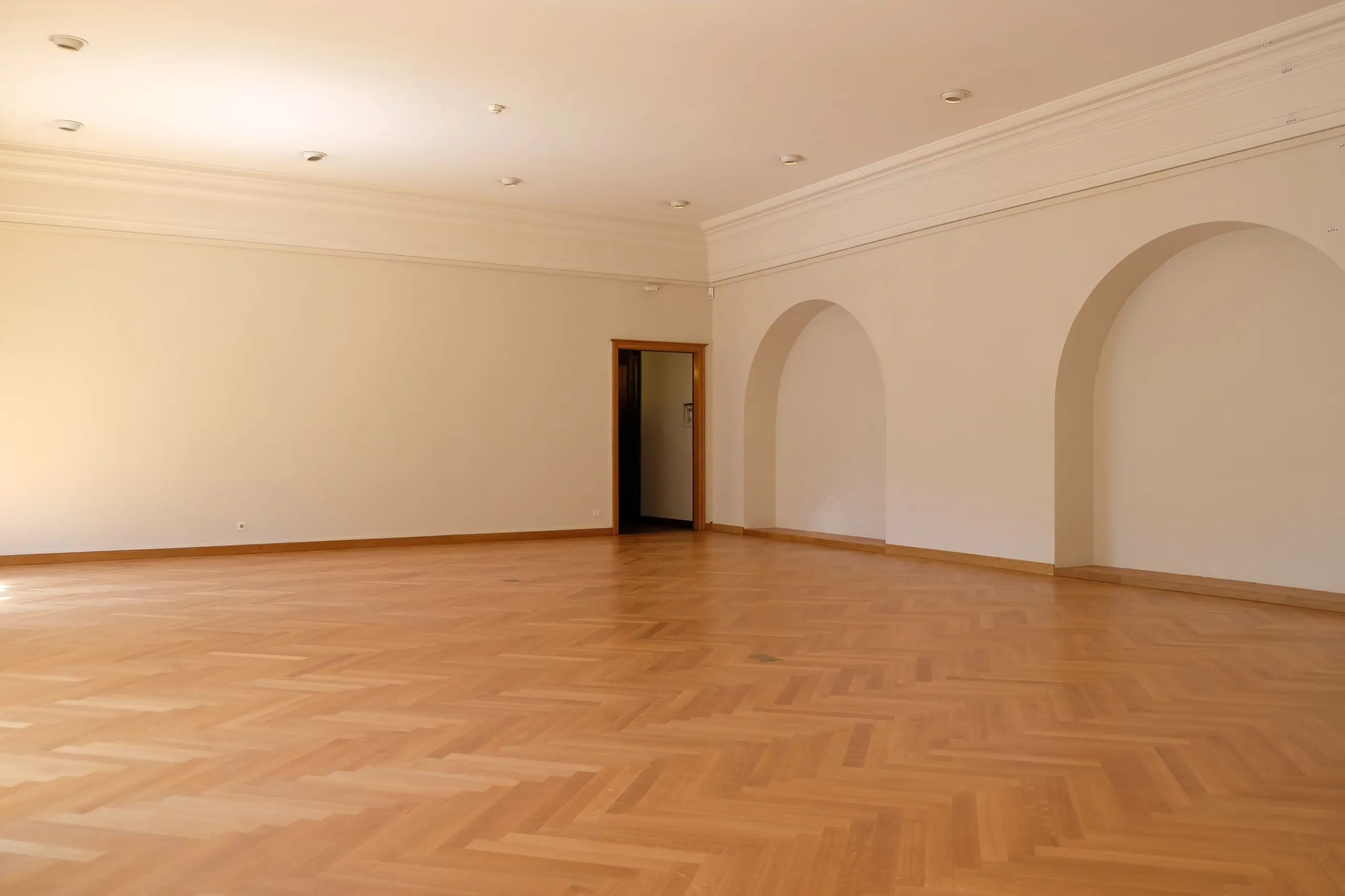 A garden room with herringbone oak floor and a run of deep arched recesses
