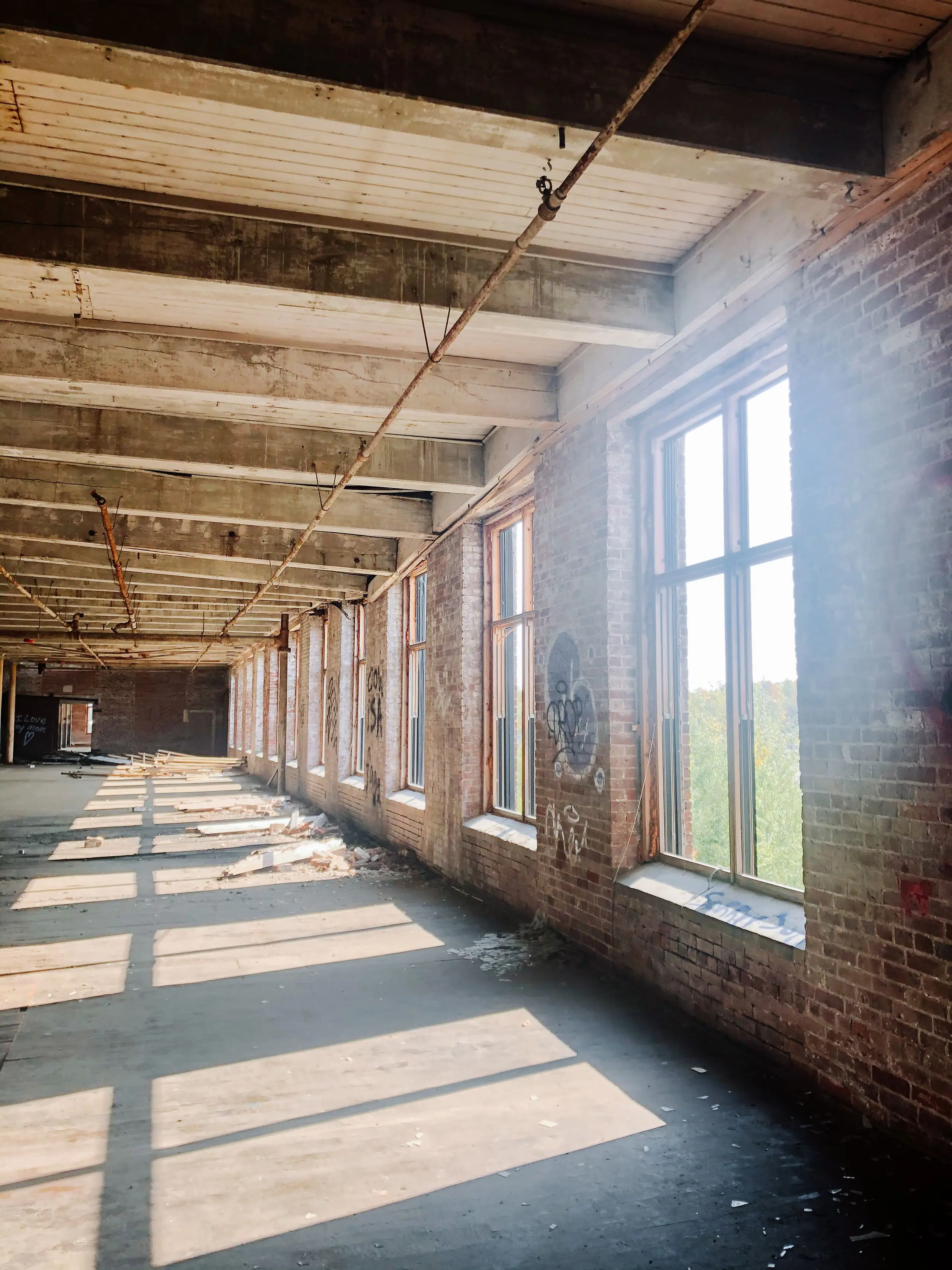A raw mill floor before the work began, with timber joists and long shafts of sunlight