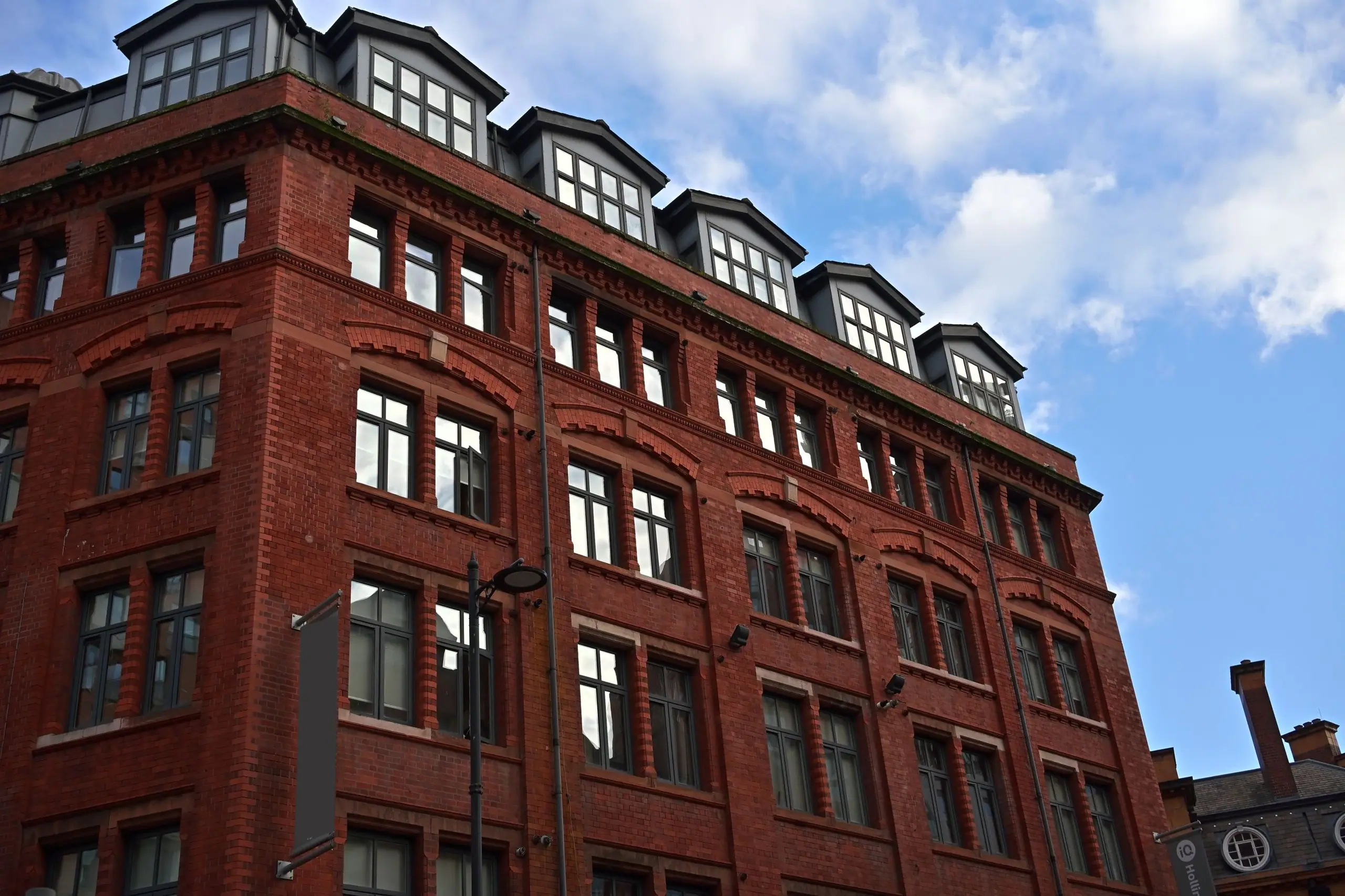 The red-brick mill exterior with its row of dormer windows against a blue sky