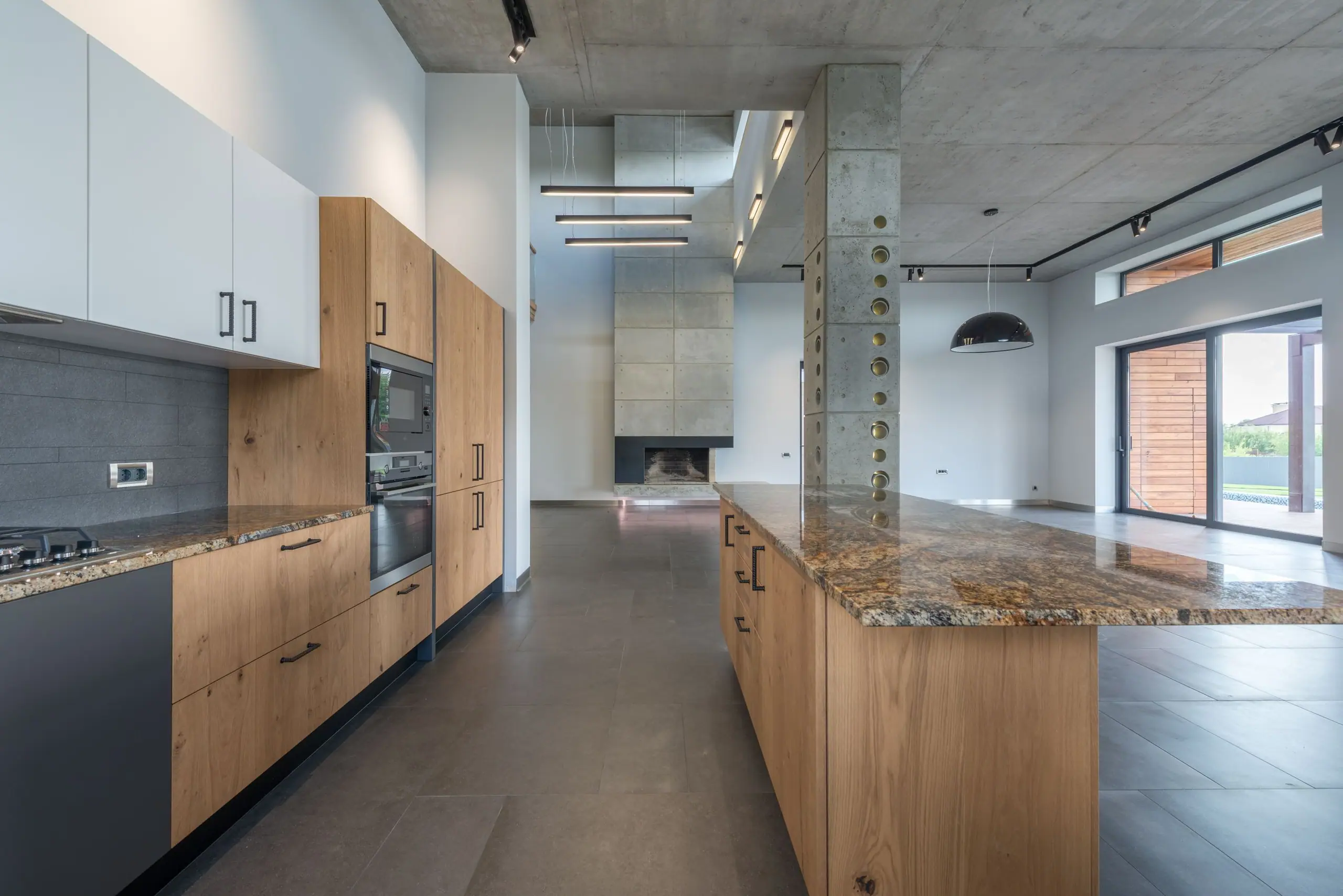 Oak kitchen run with a stone worktop beside an original concrete column