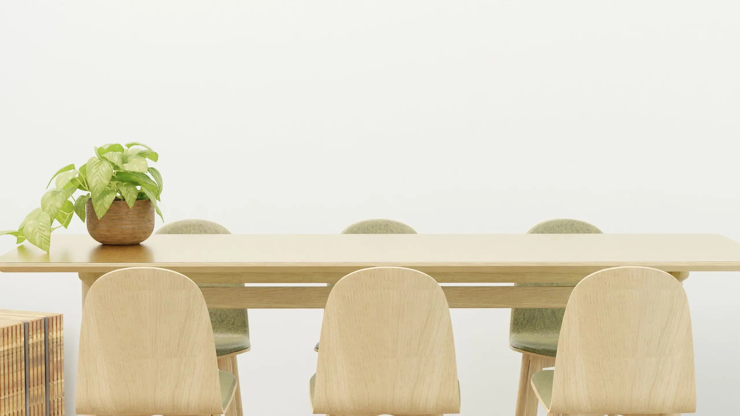 A long oak dining table with pale timber chairs against a white wall