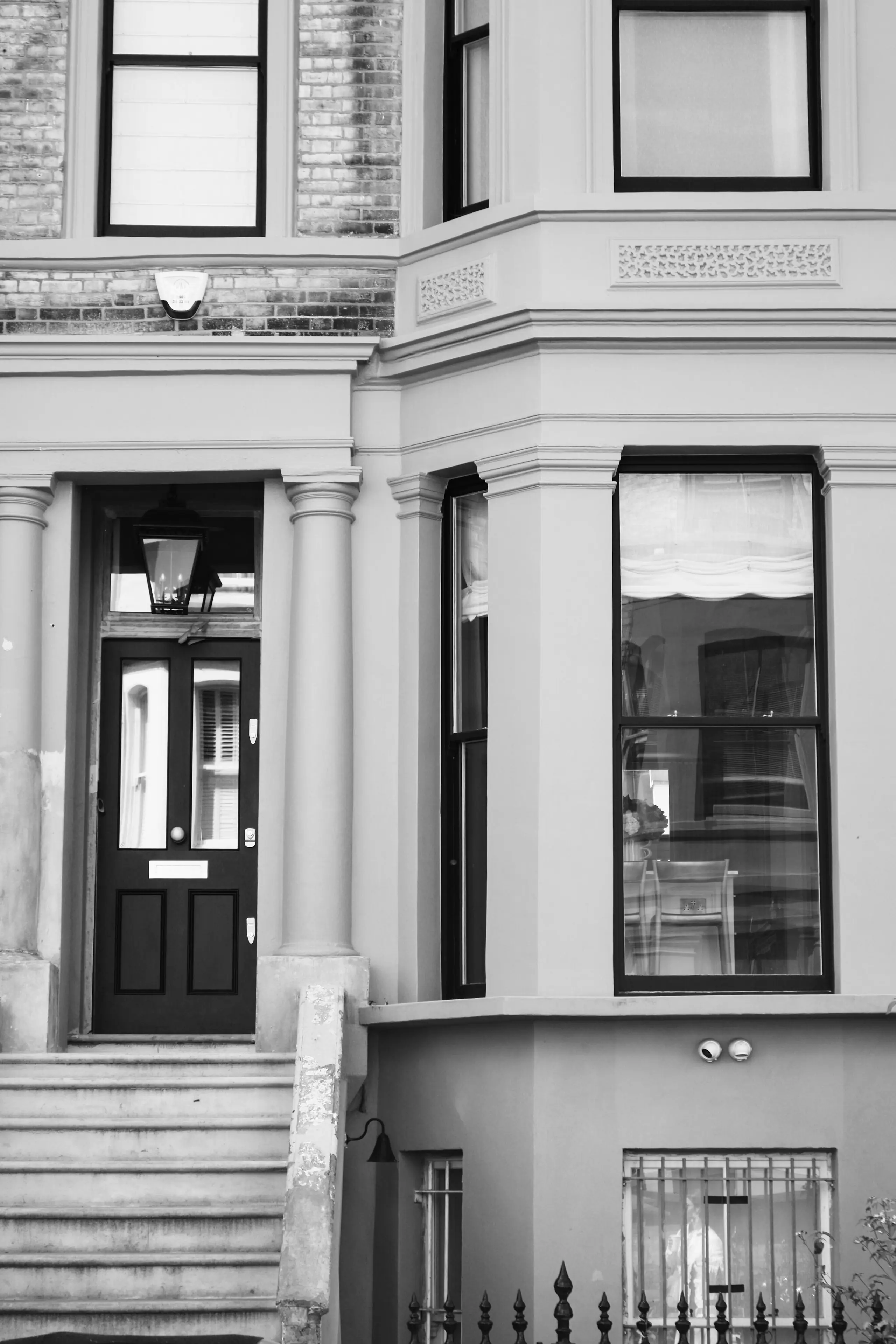 The townhouse's stucco bay and front door with its original stone steps, in black and white