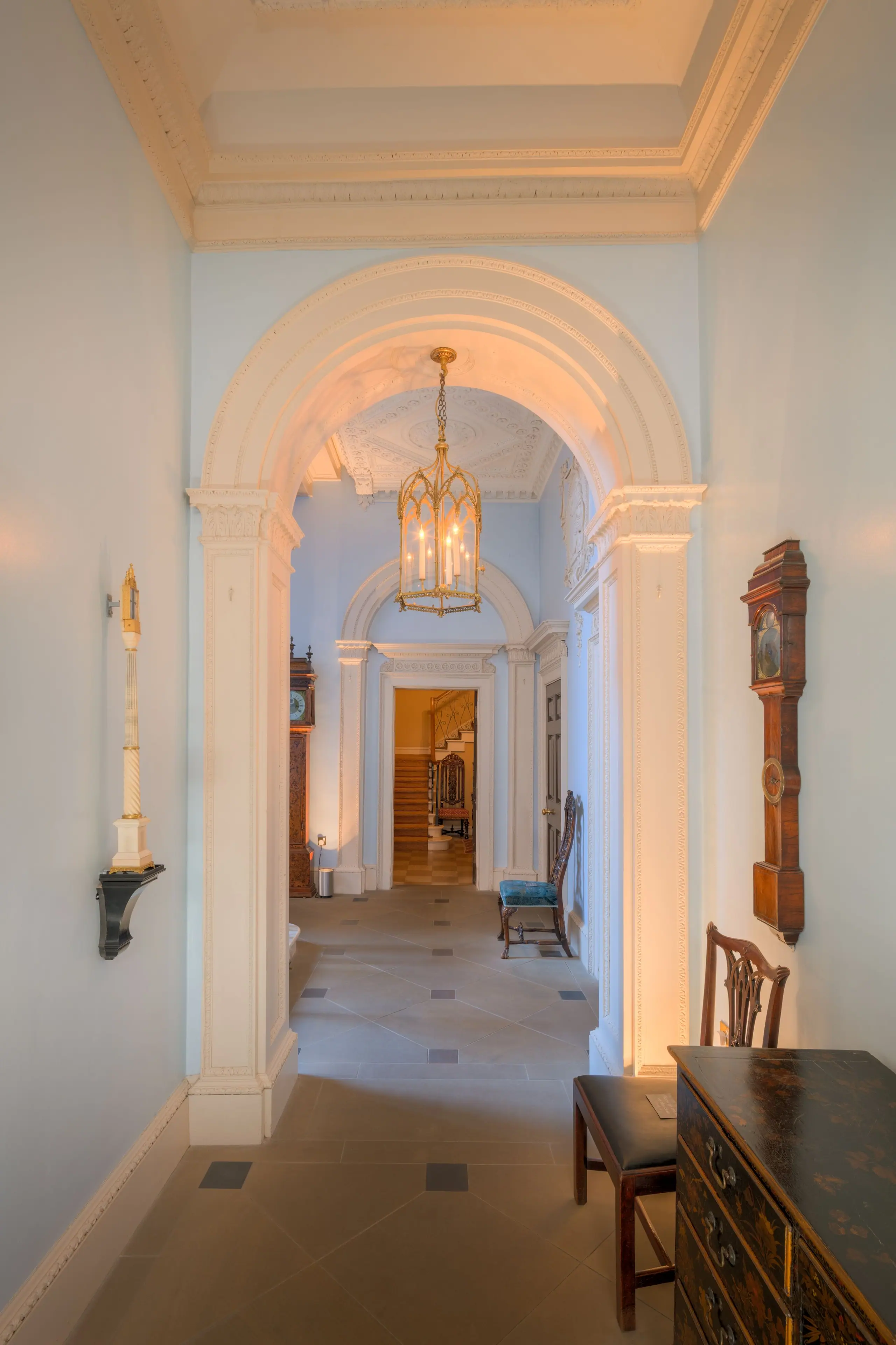 An arched Victorian hallway with restored plaster cornicing, a lantern and a stone-flagged floor leading to the stair