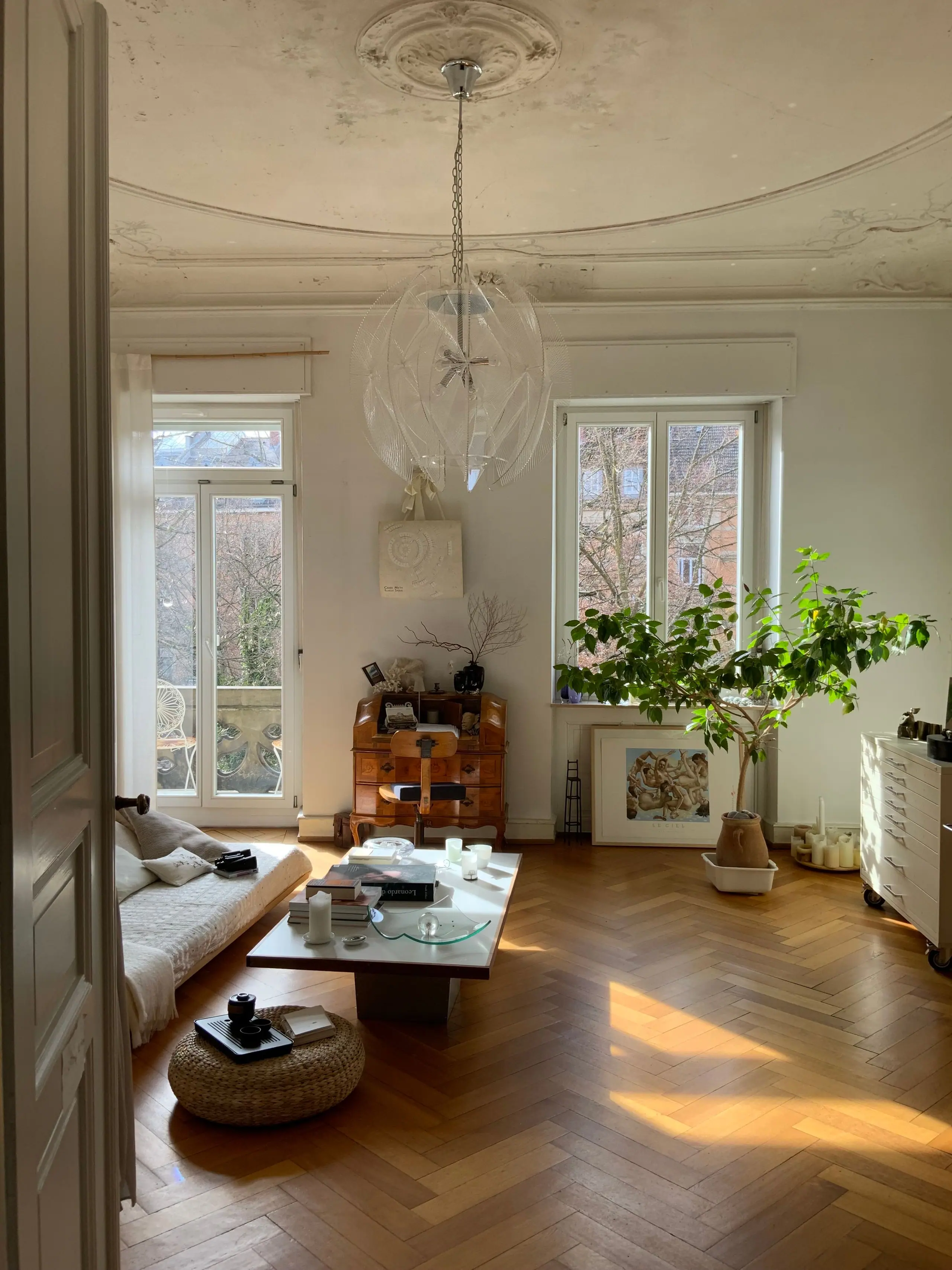 A high-ceilinged drawing room with herringbone oak floor, tall sash windows and a plaster ceiling rose
