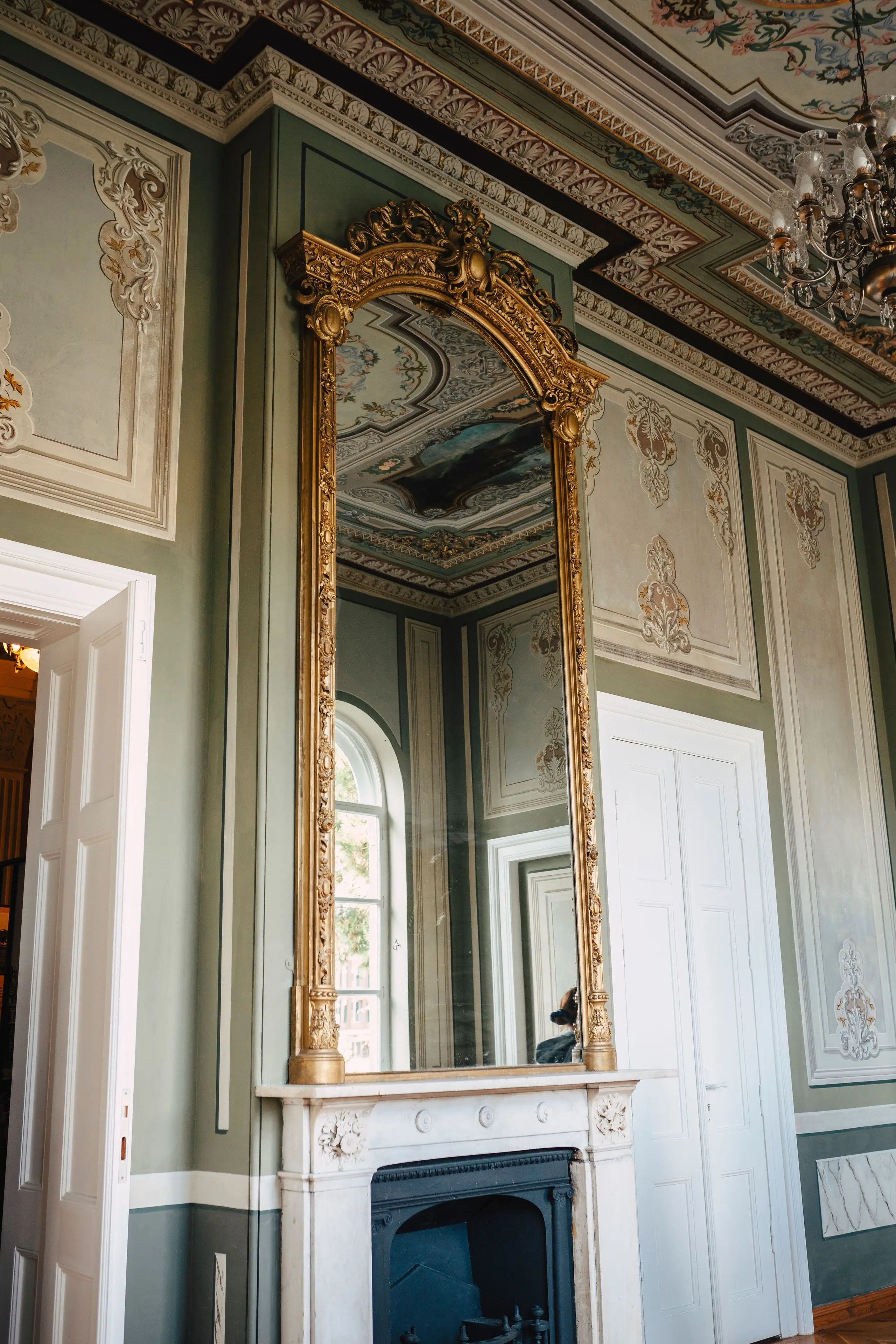 Gilded overmantel mirror and original marble fireplace in a panelled room, before restoration
