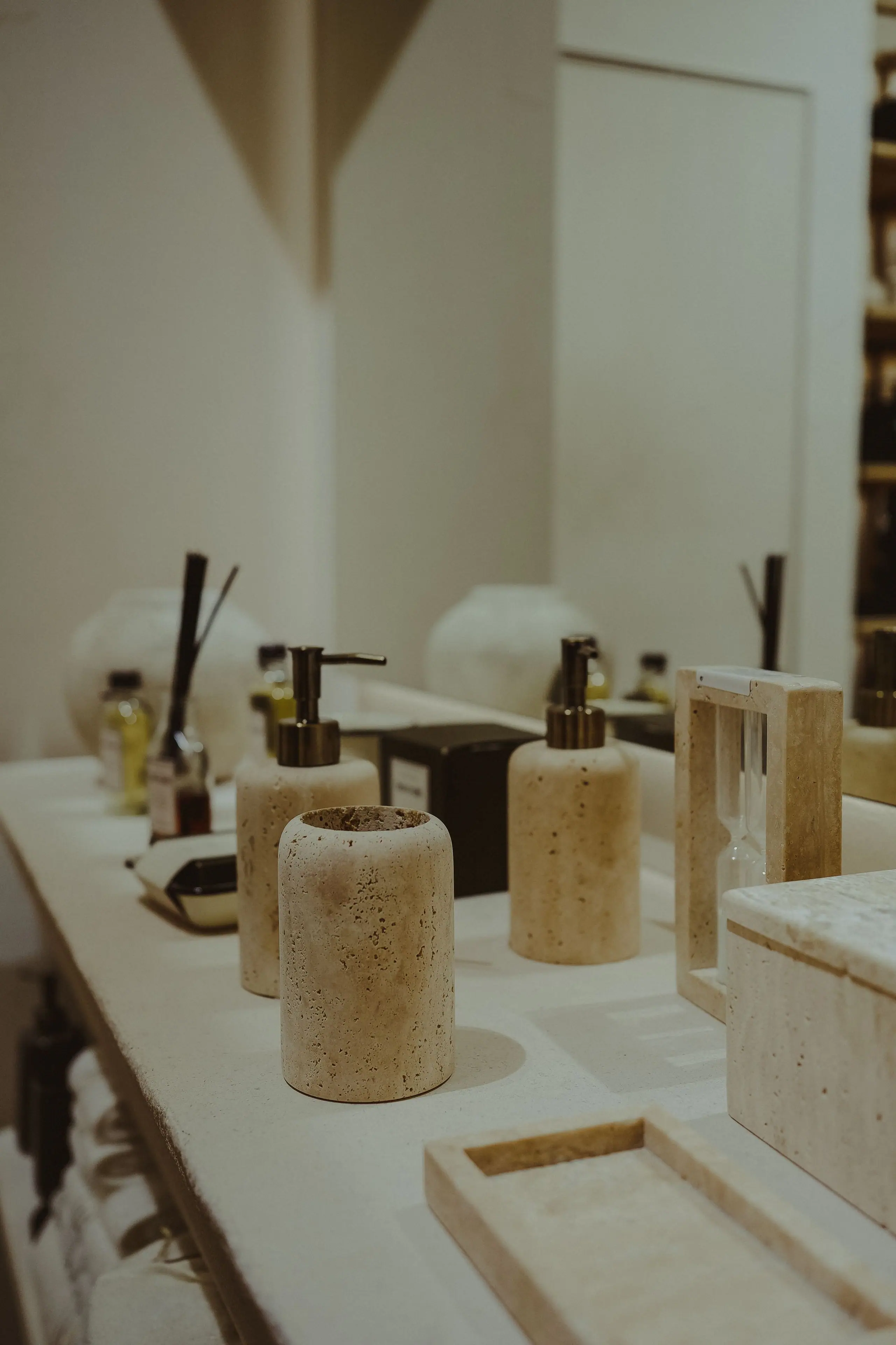 Travertine vessels and soap dispensers on a stone vanity