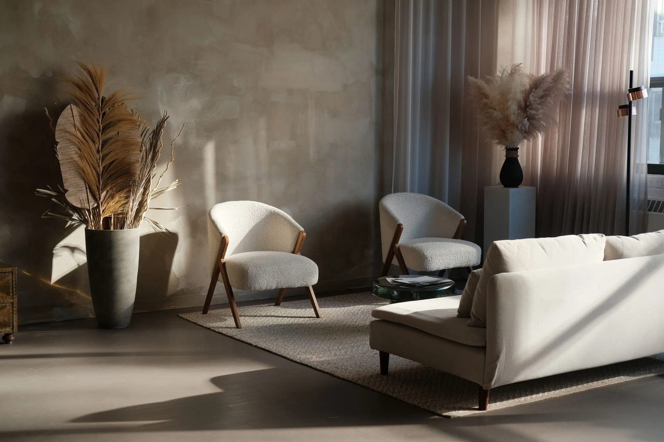 A calm living room in a converted Manchester mill: lime-plastered walls, a boucle sofa and two lounge chairs in low afternoon light