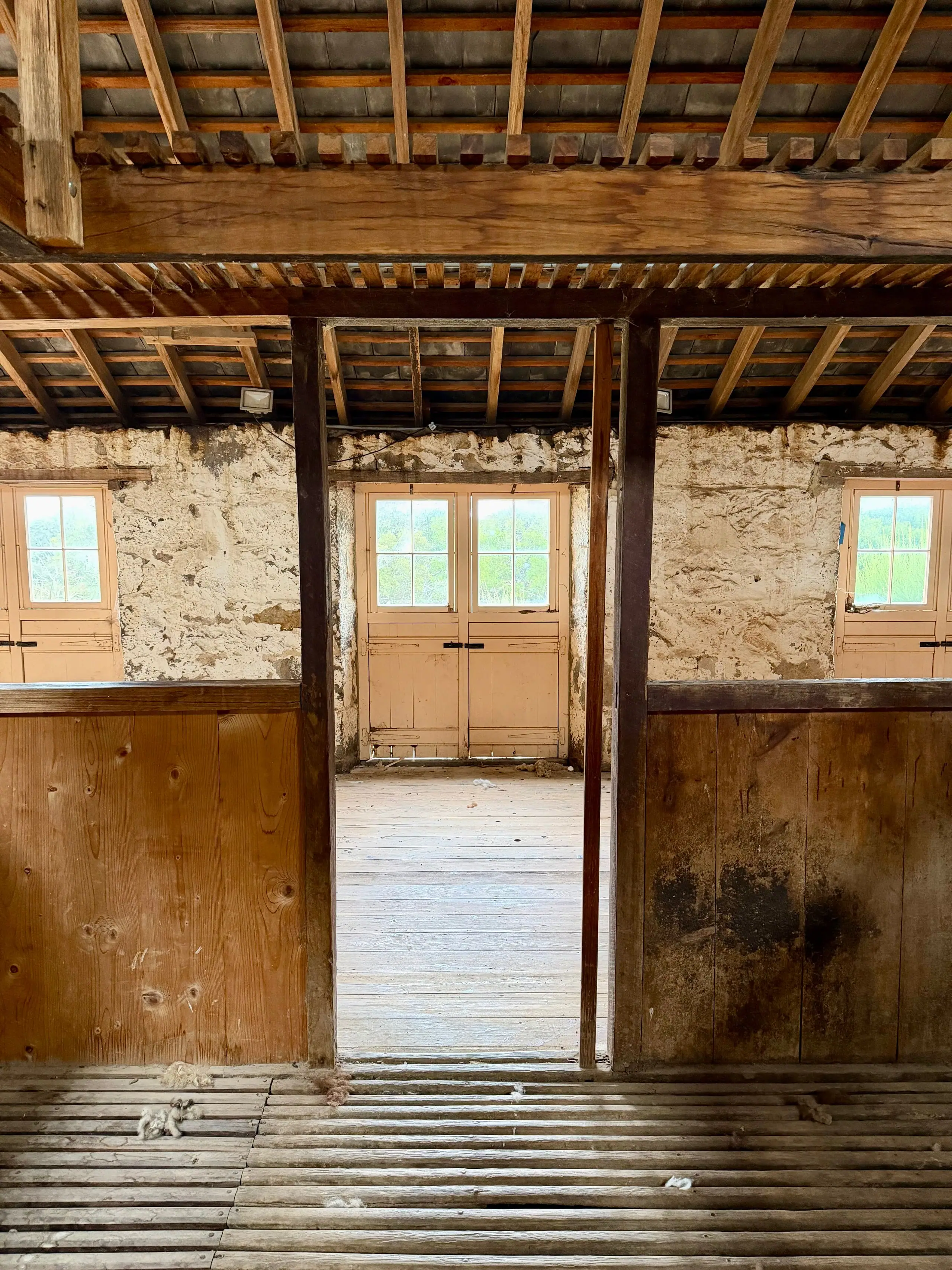 Inside the barn during the strip-out, with timber stalls and light through the old doors