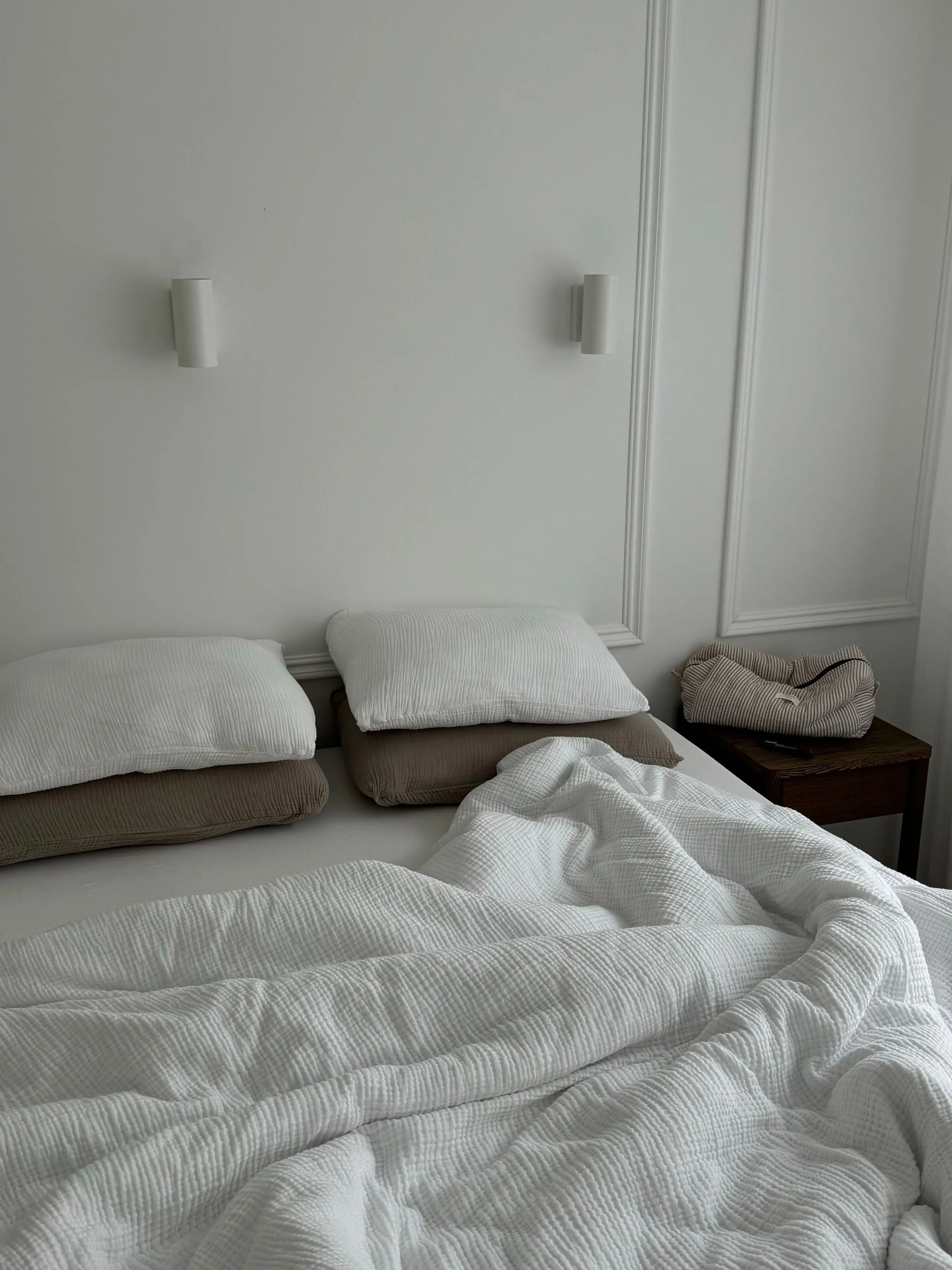 A bedroom with linen bedding and plaster-panelled walls