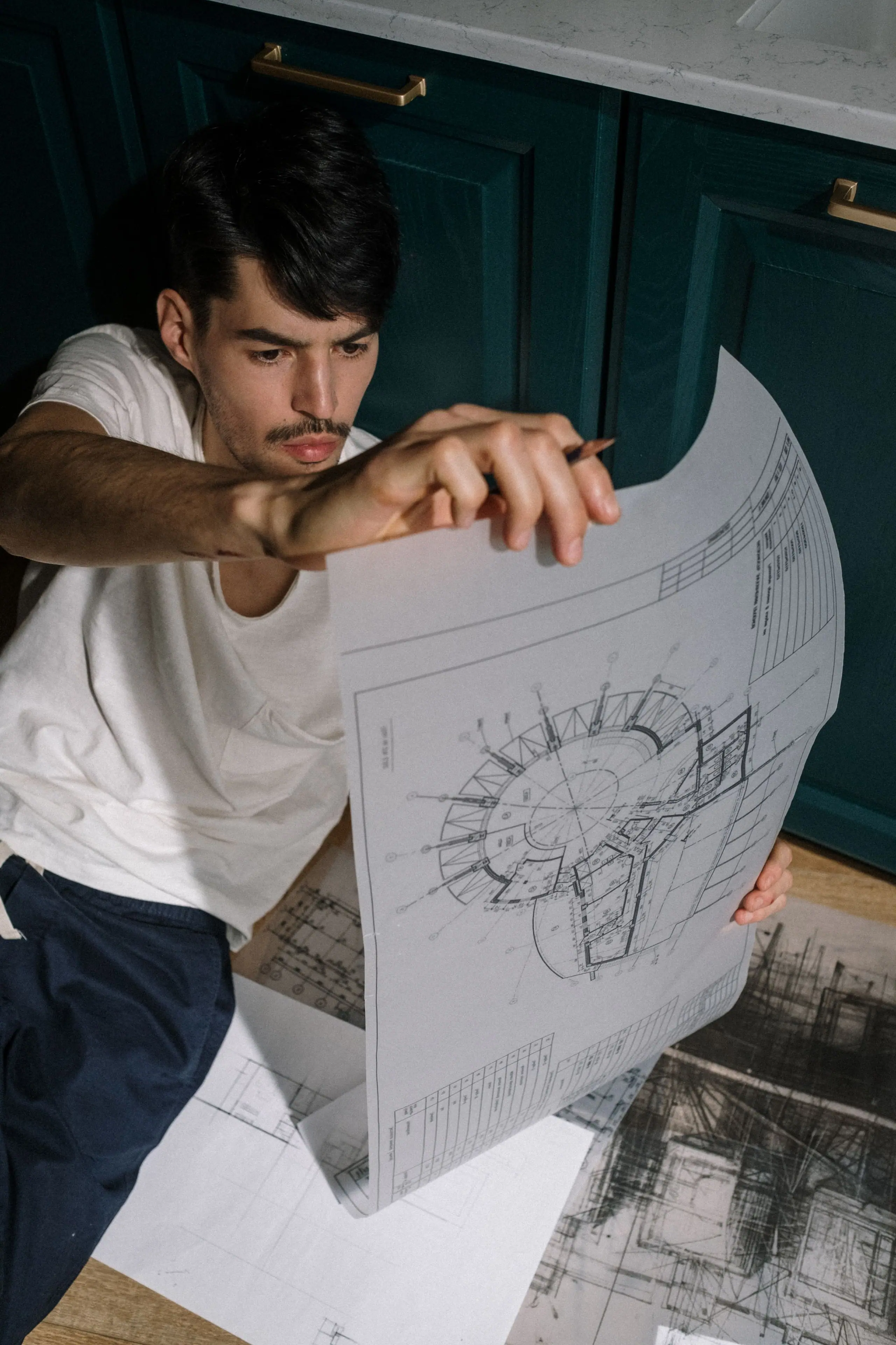 An architect holding up a large sheet of plans in the studio